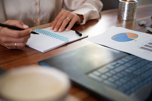 Screenshot of a woman about to take notes using a spiral-bound notepad and pen