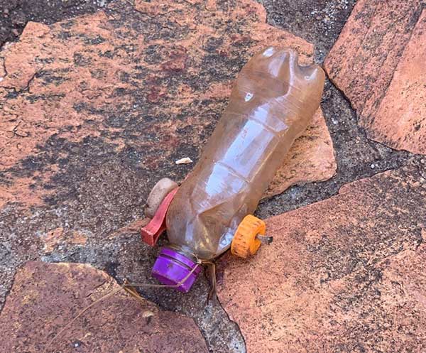 A photo of the toy car made by a young African boy made out of a water bottle with a string tied around it.