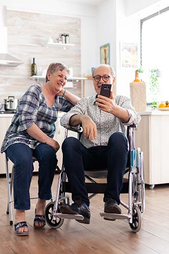 Woman and her wheelchair-bound husband using a smartphone to shop for long-term care insurance