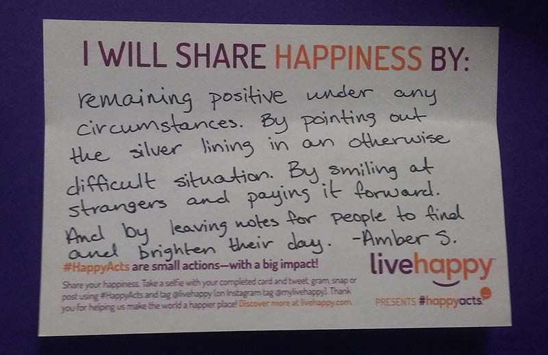 A picture of Amber S.'s note explaining how she will share happiness. It says: I will share happiness by remaining positive under any circumstances. By pointing out the silver lining in an otherwise difficult situation. By smiling at strangers and paying it forward. And by leaving notes for people to find and brighten their day.