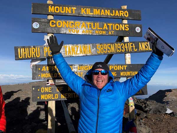 Mark Acre in front of the sign on top of Mount Kilimanjaro
