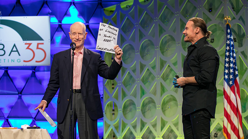 Jim Pittman receiving artist Erik Wahl's paintings of Abraham Lincoln and Marilyn Monroe at NAILBA 2016