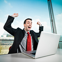 A business cheers when looking at his computer.