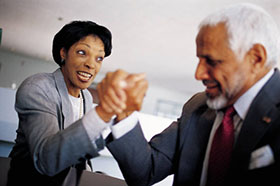 Two businesspeople arm wrestling.